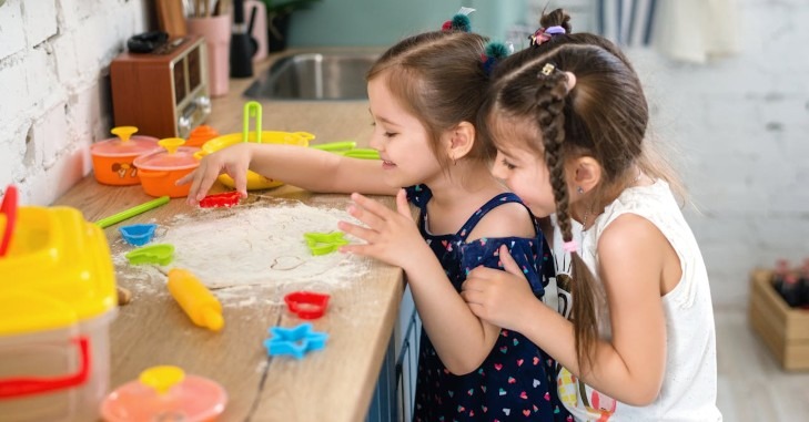 Dve devojčice se igraju sa testom u kuhinji.