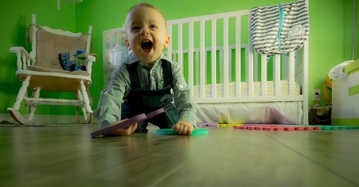 Dete se igra na podu pored kreveca.