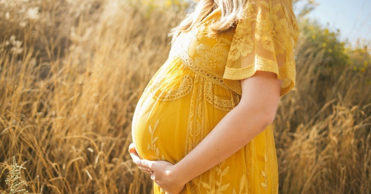 Profil trudnice koja se drži za stomak.