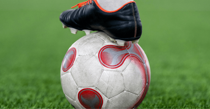 Kopačka naslonjena na fudbalsku loptu.