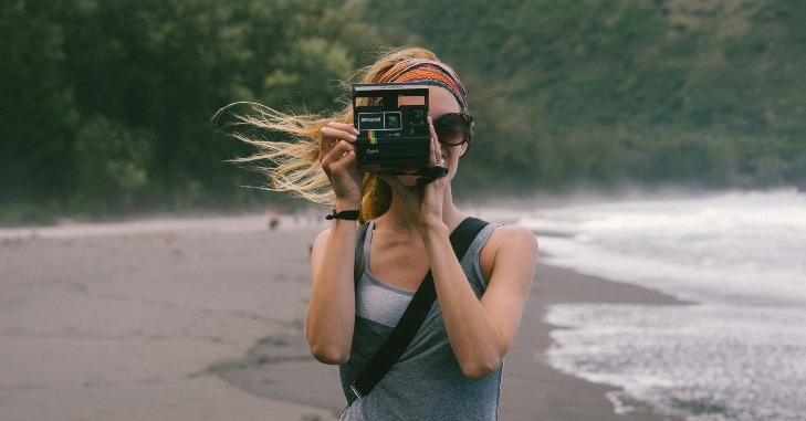 Žena slika foto-aparatom na plaži,