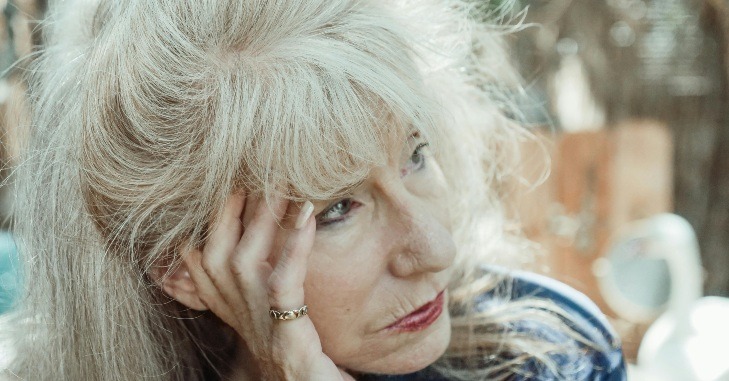 Starija žena gleda zabrinuto i drži se za glavu.