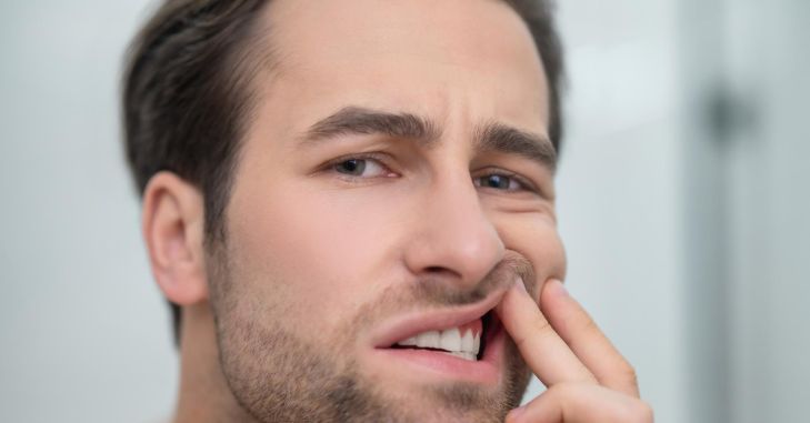 Čovek sa bolnom grimasom na licu dodiruje desni