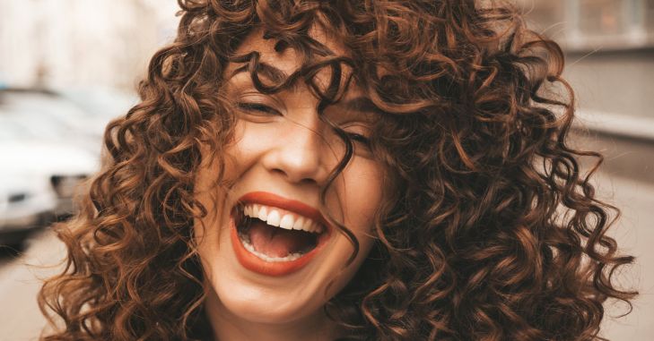 Žena sa kovrdžavom kosom se smeje